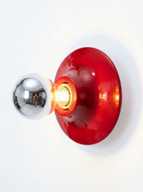 Red disc wall light seen at an angle with a chrome bulb