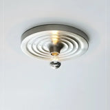 Silver ripple disc on a ceiling with the bulb lit below