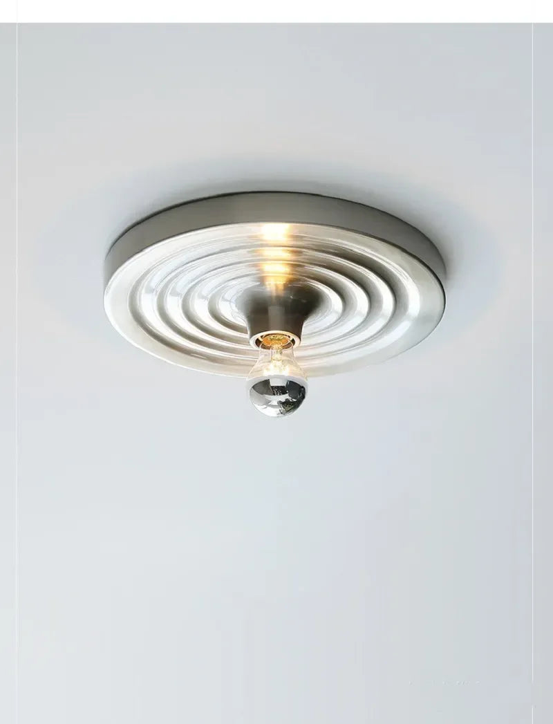 Silver ripple disc fitted to a ceiling and lit warm