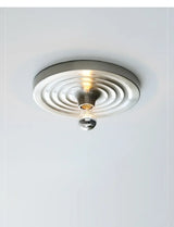 Silver ripple disc fitted to a ceiling and lit warm
