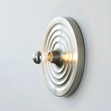 Silver ripple disc light lit warm with the bulb glowing at the centre