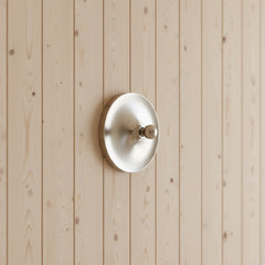 Silver disc light mounted on a pale timber clad wall