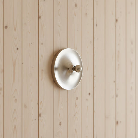 Silver disc light mounted on a pale timber clad wall