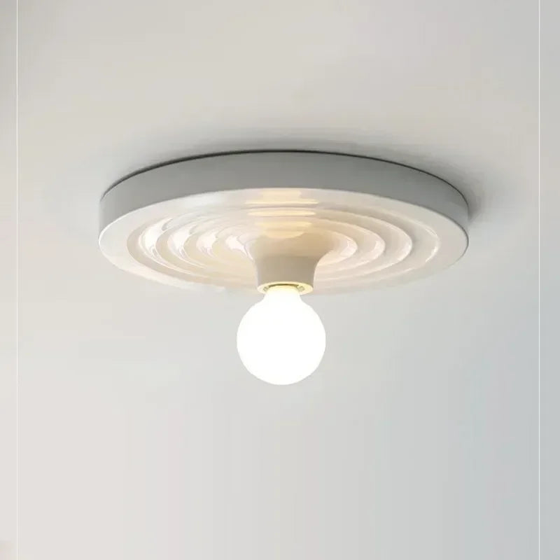 White disc light fitted to a ceiling with a round bulb below