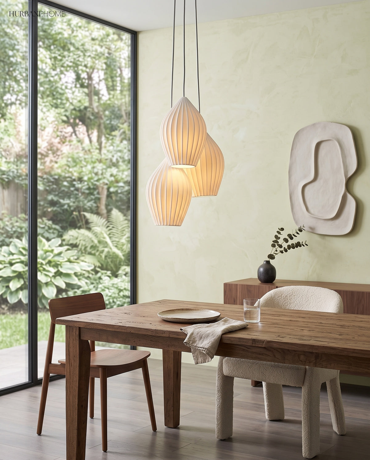 Three ribbed ceramic pendants over a timber dining table by windows