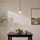 Single fluted glass pendant above a dark table against plaster walls