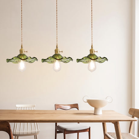 Three green scalloped glass pendants in a row above a light oak dining table