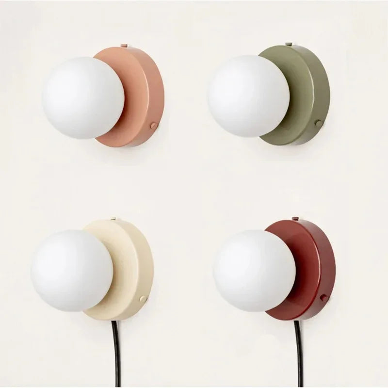 Four frosted glass globe wall lamps in terracotta, olive, cream and red