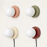 Four frosted glass globe wall lamps in terracotta, olive, cream and red