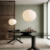 Two pebble pendants lit above a dark round dining table