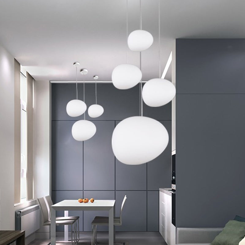 Pebble pendants lit at mixed heights in a grey and white kitchen