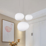 Three pebble pendants lit above a hallway beside framed art
