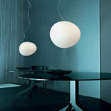 Two pebble pendants lit above a dark table on a teal wall