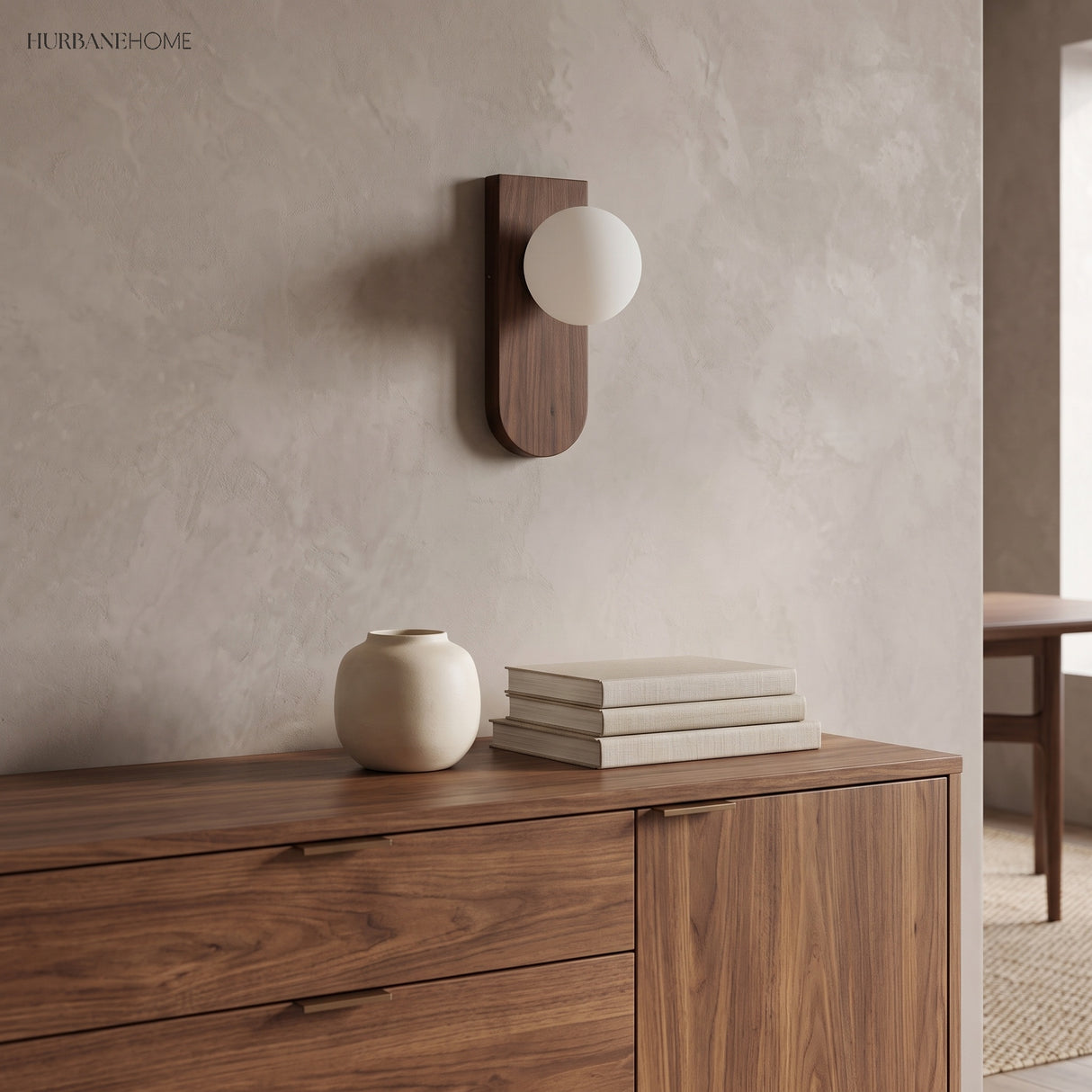 Frosted glass wall sconce above a walnut sideboard with vase and books