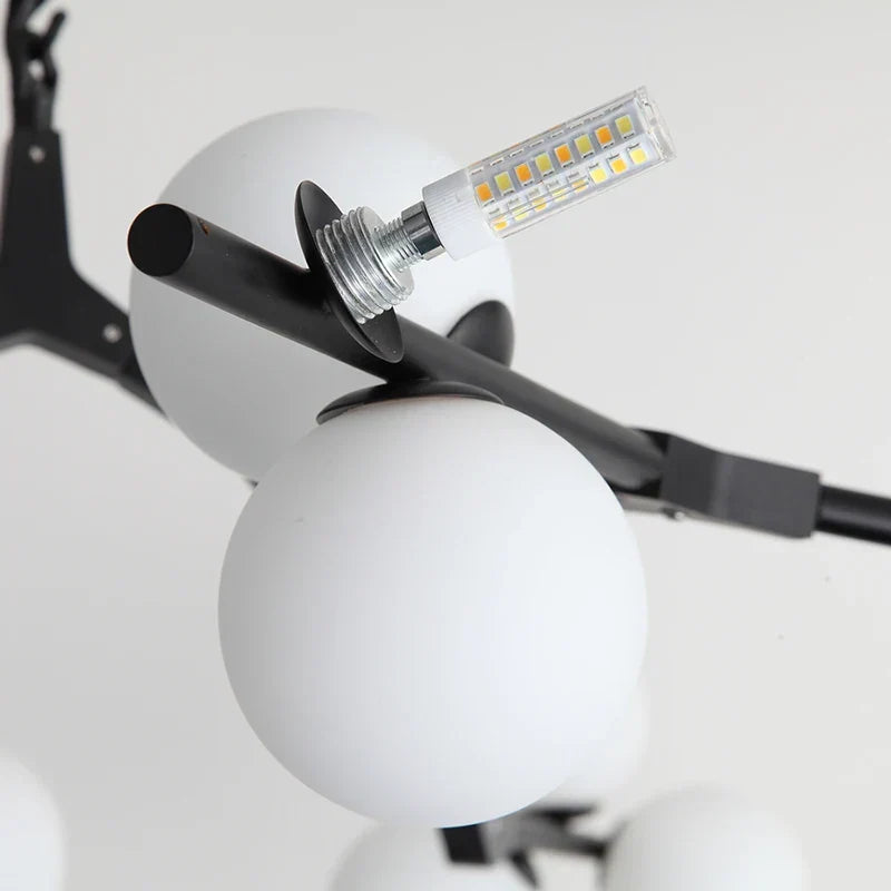 A bulb being fitted into a frosted glass globe on a black arm
