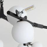 A bulb being fitted into a frosted glass globe on a black arm