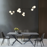 Black branch chandelier above a grey dining table and four chairs