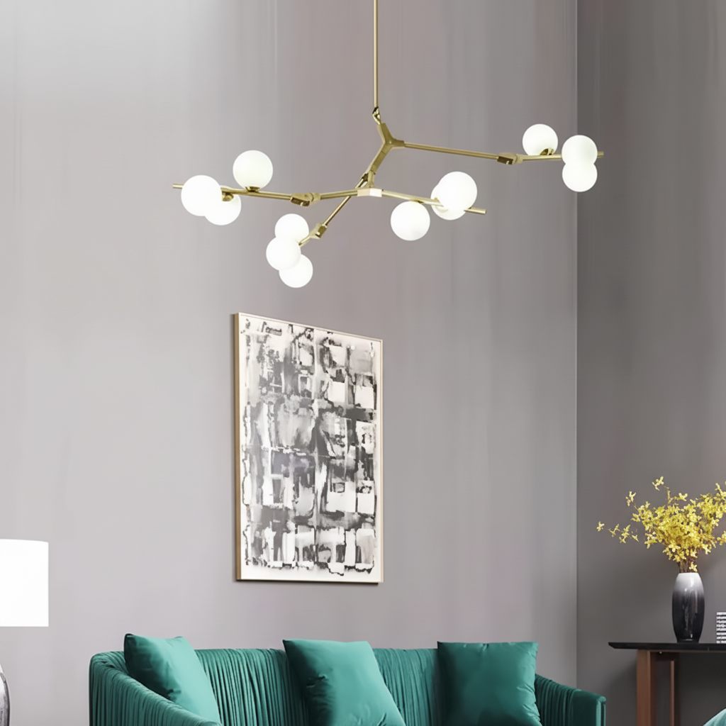 Gold branch chandelier above a green sofa beside framed artwork