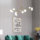 Gold branch chandelier above a green sofa beside framed artwork