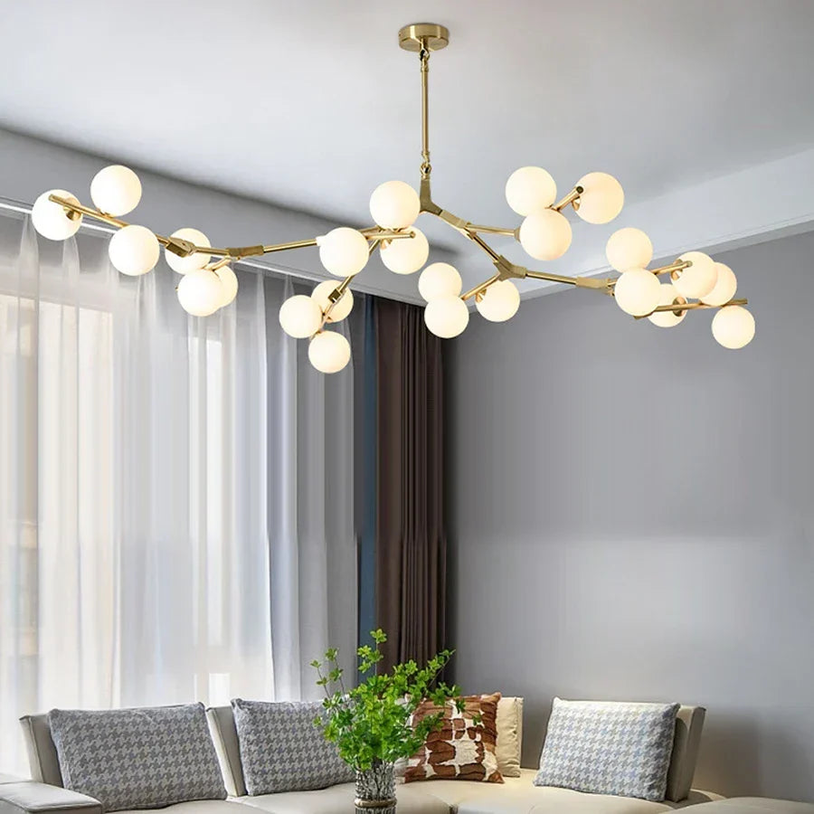 Gold branch chandelier lit above grey sofas in a bright living room