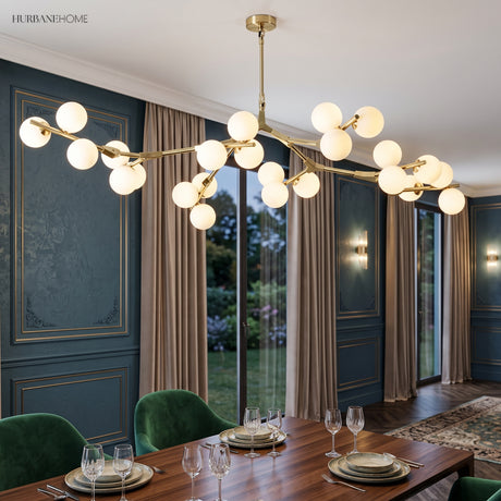 Gold branch chandelier lit above a dining table in a navy panelled room