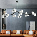 Black branch chandelier with glass globes above a burnt orange sofa