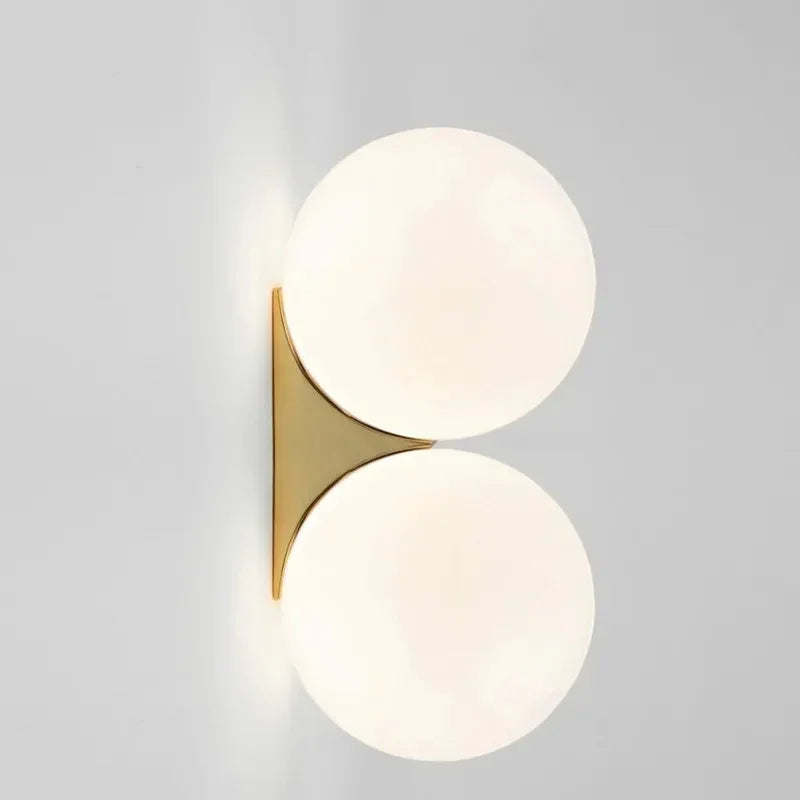 Two frosted glass globes stacked on a gold wall bracket