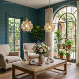 Two clear glass flower pendant lights lit above a plant-filled living room