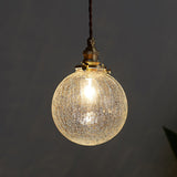 Crackle glass sphere pendant glowing warm against a dark grey background