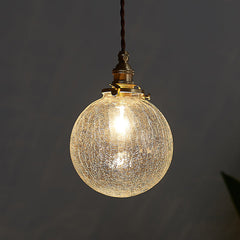 Crackle glass sphere pendant glowing warm against a dark grey background