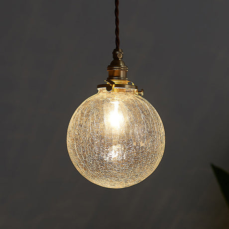 Crackle glass sphere pendant glowing warm against a dark grey background