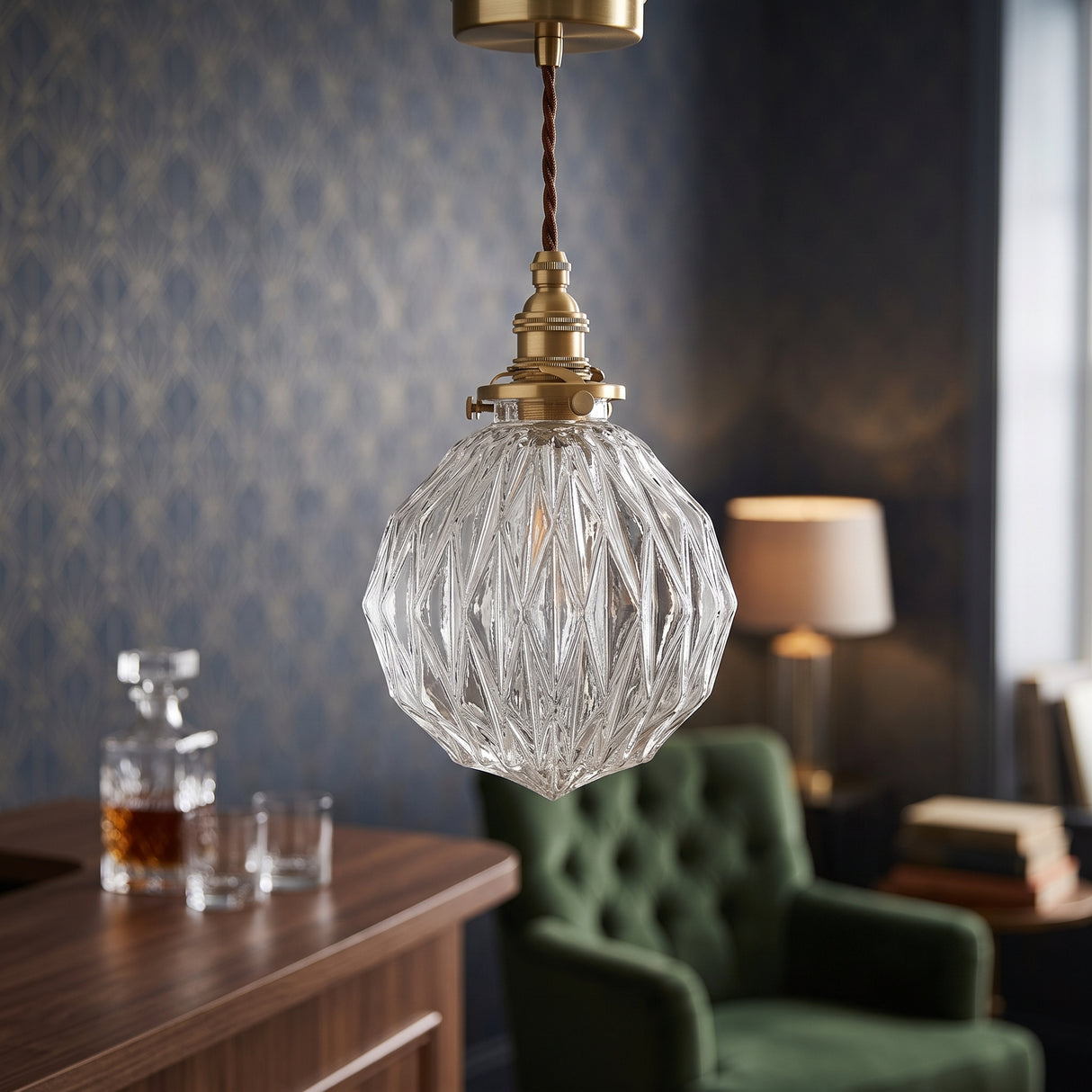 Faceted clear glass globe pendant lit above a dark navy dining wall