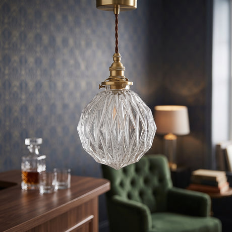 Faceted clear glass globe pendant lit above a dark navy dining wall