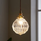 Faceted glass globe pendant lit close up against a pale wall