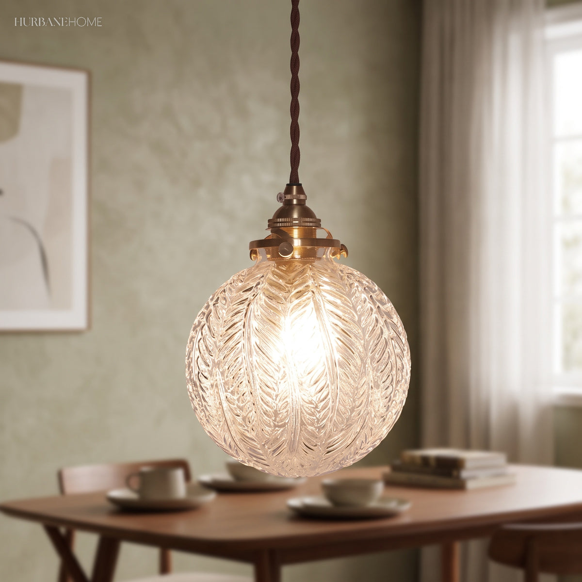 Leaf patterned glass globe lit above a dining table on green