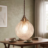 Leaf patterned glass globe lit above a dining table on green