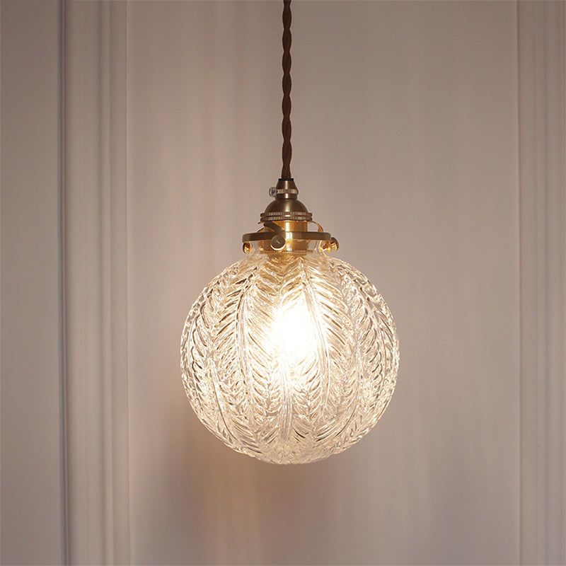 Leaf patterned glass globe lit close up on a panelled wall