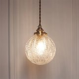 Leaf patterned glass globe lit close up on a panelled wall