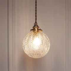 Leaf patterned glass globe lit close up on a panelled wall