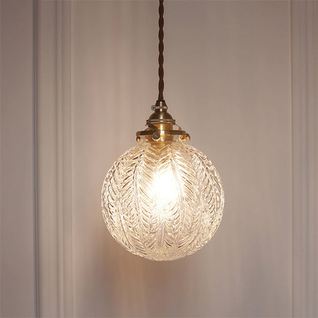 Leaf patterned glass globe lit close up on a panelled wall