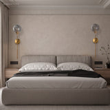 Two clear glass globe wall lights above a bed on a plaster wall