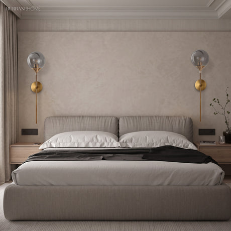Two clear glass globe wall lights above a bed on a plaster wall