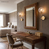 Clear glass globe wall sconces beside a wall-mounted screen in a bedroom