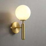 Gold wall sconce with a milk glass globe against a plain grey wall