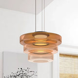 Amber three-layer glass pendant light against a near-plain white wall with art