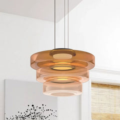 Amber three-layer glass pendant light against a near-plain white wall with art