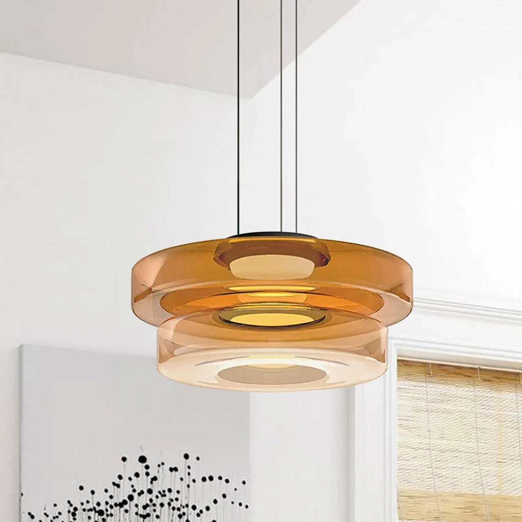 Amber two-layer glass pendant light against a near-plain white wall with art