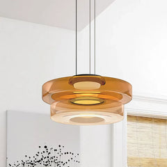 Amber two-layer glass pendant light against a near-plain white wall with art