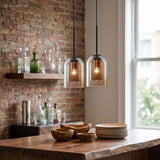 Two double glass pendants lit above a brick walled kitchen bench