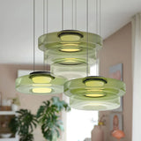 Cluster of green mixed-layer glass pendant lights in a bright room with a plant